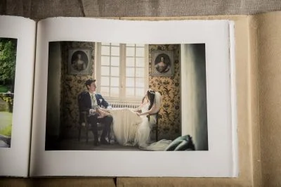 Tirage d'art dans album photo mariage, mariés assis près d'une fenêtre