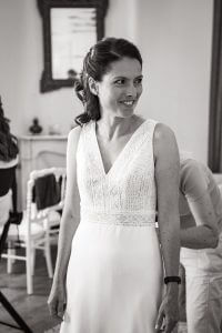 Mariée souriante enfilant sa robe, préparatifs mariage au Château de la Beaumetane
