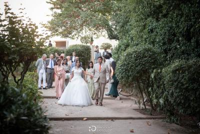 Mariée et invités marchant dans une allée verdoyante, mariage Magnanerie Saint Isidore