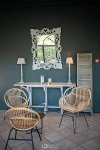 Console en bois avec lampes et miroir ouvragé, fauteuils en rotin, Magnanerie Saint Isidore