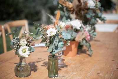 Bouquets champêtres en vases sur table bois, décoration mariage Mas des Costes