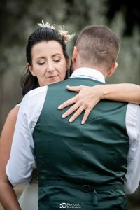 Mariée émue enlaçant un proche en gilet vert, moment tendre au Mas des Costes