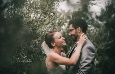 Mariage moody à Marseille, couple enlacé et souriant parmi le feuillage d'oliviers