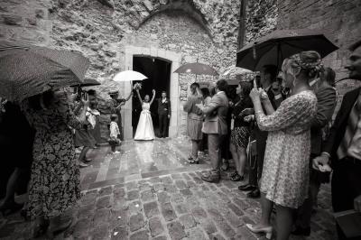 Mariage pluvieux, mariée avec parapluie entourée d'invités, Bastide Saint Julien
