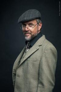 Portrait studio style vintage d'un homme en costume avec des lunettes et casquette plate