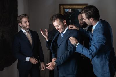 Groom getting ready with his groomsmen adjusting his jacket